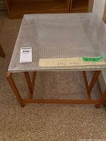 Top view of the square glass top covered in bubble wrap on wooden side table base.