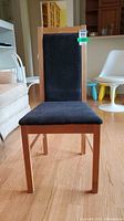 Front view of the IKEA chair showing black upholstered seat and back with light wood frame.