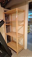 Full view of the wooden shelving unit showing four shelves, wooden frame in natural light wood color.