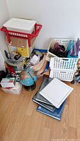 Photo showing assorted office supplies on floor: blue globe, white and red baskets, binders, and papers.