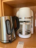 Oster electric kettle and KitchenAid white coffee maker side by side.