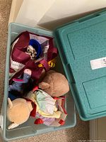Plastic tub with multiple plush toys and bags holding stuffed animals inside.