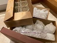 Boxed set of clear glass mugs wrapped and protected in cardboard boxes with some packing materials.