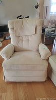 Front view of beige fabric recliner rocker chair showing cushioned armrests and button-tufted backrest