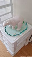 Polar bear figurine standing on the glass base showing front and side details of the ceramic figure and glass with wavy edge.