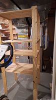 Side angle photo showing the wooden shelving with 4 shelves and cross-bracing wires, placed in a basement setting.