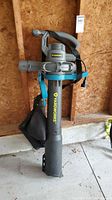 Front view of the Yardworks corded electric leaf blower/vacuum standing upright showing the full unit with shoulder strap and collection bag attached.