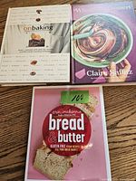 Three baking cookbooks on wooden floor: 'On Baking', 'What's for Dessert', and 'Bread & Butter'.