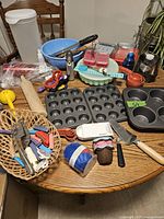 Full overview of the baking items collection on the table including pans, cookie presses, torch, measuring spoons and many small tools.