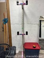 Photo of an empty metal double bike rack mounted on a wall, showing the structure of the rack with padded contact points.