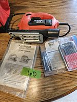 Black & Decker jigsaw on wooden table with instruction manuals and a green sticker labeled '60'