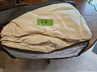 Folded queen size duvet inside a transparent storage bag with black trim on a wooden surface.