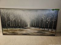Full view of the framed wall art showing a monochromatic forest scene with rows of trees and a pathway, in grayscale with texture details.