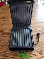 Open George Foreman grill showing ridged non-stick cooking plates inside.