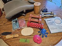 Photo of the lot showing back support pillow, dumbbells, hand weights, bamboo aromatherapy diffuser, massage rollers and massagers, exfoliating and pumice stones, brushes, and packaged health items.