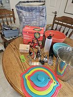 Photo of the full lot on a round wooden table including bowls, bar tools, silicone lids, Instant Pot Essential Accessories Set, and ice bucket.