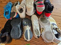 Overview of six pairs of Nike runners, showing soles and uppers, various colors including black, white, blue and red accents.