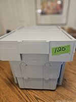 White slide-out frame housing two vertical removable grey plastic baskets, closed front view with handle on top.