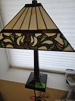 Side view of Tiffany-style table lamp showing stained glass shade with floral pattern and dark sturdy base.