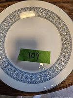 Close-up image of one dinner plate showing the intricate blue floral rim pattern on white porcelain.