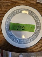 Top view of one white porcelain luncheon plate with a detailed light blue floral and geometric border pattern.