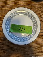 Top down photo of a white Wedgwood side plate showing the detailed blue floral and geometric band around the edge with silver trim.