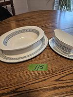 Photo showing a Wedgwood Counterpoint pattern large oval platter, oval serving bowl, and matching gravy boat with attached underplate on a wooden table.
