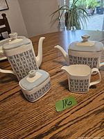 Photo of Wedgwood Counterpoint coffee pot, tea pot, creamer, and sugar bowl on wooden table showing distinct blue patterned panels and white lids.