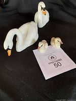 Family group of four Beswick swan figurines on black cloth