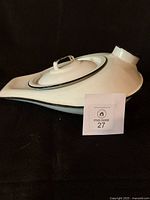 Side view of enamel bedpan with lid and spout