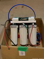 Front view of Elite filtration system in box showing three filter housings and tubing