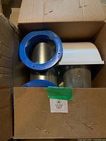 Box contents showing blue collars, metal ducts, white wall hoods
