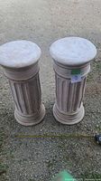 Pair of white-washed clay fluted pedestal columns standing side by side outdoors