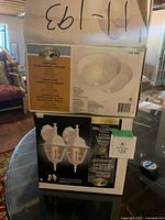 Two boxed Hampton Bay lighting twin packs stacked, wall lantern pack visible