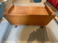 Side view of rectangular pine box on two legs with lid closed