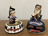 Front view of two hand painted Betty Boop sculptures on a flat surface showing detailed features.