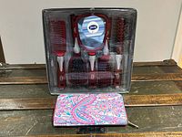 Packaged Goody hair brush set with multiple brushes and hand mirror in red and white color scheme, plus a colorful paisley wallet