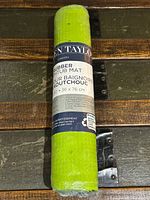 Rolled green rubber bathmat in original packaging displaying product label with size and branding.