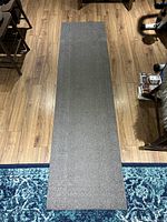 Full view top down of the grey carpet runner laid on wooden floor from above showing overall length and texture.