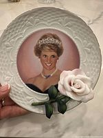Front view showing the portrait of Princess Diana in the center with the attached porcelain rose on the lower right edge.