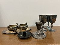 Photo showing entire silver plated set with 4 goblets, candlestick, creamer, sugar bowl on tray, and black wooden rolling pin