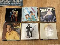Top view of six vinyl album records showing titles and artists: Flashdance, The Supremes & The Four Tops, Tom Jones, Andy Williams, Neil Diamond, Barry Manilow.