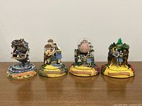 Four Wizard of Oz musical figurines in a line on a tabletop showing front view with clear visibility of each base label and characters.