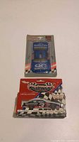 Lot contents showing unopened Ford Quality Care NASCAR license plate and limited edition Dale Earnhardt Sr. porcelain ornament in original packaging.