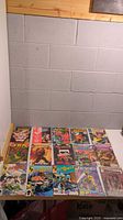 Photo showing all 15 assorted comic books laid out on a wooden surface beneath a white wall.