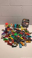 Photo showing wide array of approximately 50 assorted die-cast toy cars and vehicles including character cars and a new Hot Wheels Forza Motorsport Ford GT in package.