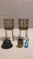 Full view of all five items: two decorative candle holders, black service bell, miniature barrel, and blue glass bottle.