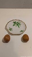 Top view of two potato-shaped salt and pepper shakers and white plate with green floral design and gold trim
