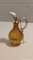 Full view of the vintage Italian vinegar jug marked "ACETO" with metal spout and handle, cork stopper chained to the handle.