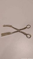 Full view of vintage silverplated salad tongs showing scissor style and looped handle